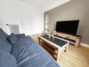 ein Wohnzimmer mit einem blauen Sofa und einem TV in der Unterkunft Élégant Pied-à-Terre à Beauvais in Beauvais