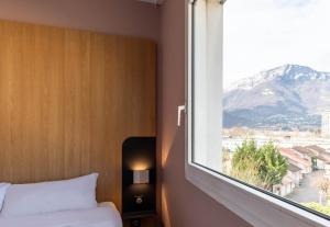 - une chambre avec une fenêtre offrant une vue sur la montagne dans l'établissement B&B HOTEL Grenoble Centre Verlaine, à Grenoble