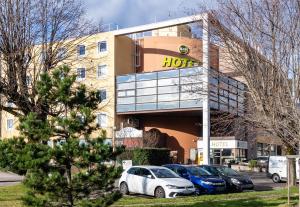 un hôtel avec des voitures garées devant lui dans l'établissement B&B HOTEL Grenoble Centre Verlaine, à Grenoble