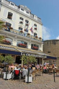 un grupo de personas sentadas en mesas frente a un edificio en Hôtel France et Chateaubriand, en Saint-Malo