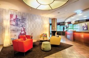 a lobby with two chairs and a table and a bar at Leonardo Hotel Mannheim City Center in Mannheim