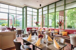 a restaurant with tables and chairs and large windows at Leonardo Hotel Mannheim City Center in Mannheim