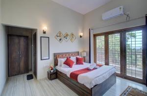 - une chambre avec un grand lit et des oreillers rouges dans l'établissement TAJ VILLA Mahabaleshwar, à Mahabaleshwar