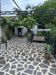 a stone patio with a bench and a pergola at Apartment Lui in Tbilisi City