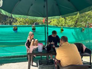 een groep mensen die aan een tafel zitten onder een paraplu bij Tiny Spot Hostel in Manāli