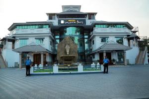 Dois homens de uniforme em frente a um edifício. em Hotel Savera Park em Thrissur