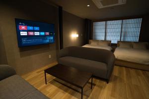 金沢市にあるMusashi Condo Kanazawaのベッド2台、ソファ、テレビが備わる客室です。