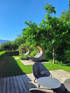 a wooden deck with chairs and tables in a garden at Pension Hasslhof in Caldaro