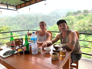 a man and a woman sitting at a wooden table at Dragonfly Senaru Lodge in Senaru