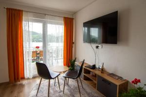 sala de estar con mesa, sillas y TV en Villa Pliva Lake, en Jajce