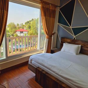 a bedroom with a bed and a large window at Roof Top Resort in Murree