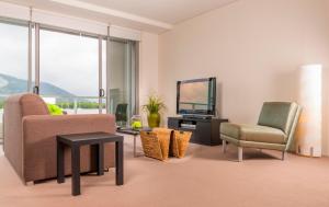 ein Wohnzimmer mit einem Sofa, einem Stuhl und einem TV in der Unterkunft Cairns Private Apartments in Cairns