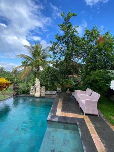 una piscina con un sofá púrpura junto a una piscina en Dukuh Village Villas & Art, en Tegalalang