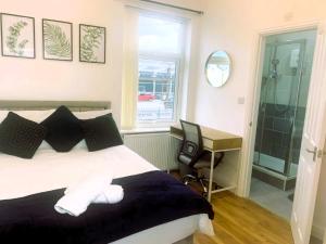 1 dormitorio con cama, escritorio y ventana en Newly renovated 3 Ensuite bedroom house in bury, 5 people, en Bury