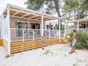 a family standing on the deck of a house at Mobile homes in Zaton Holiday Resort, with large pool area in Zaton