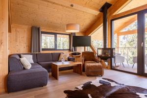 a living room with a couch and a tv at Alpenchalets Reiteralm by ALPS RESORTS in Schladming