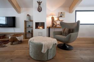 a living room with a chair and a ottoman at Alpenchalets Reiteralm by ALPS RESORTS in Schladming