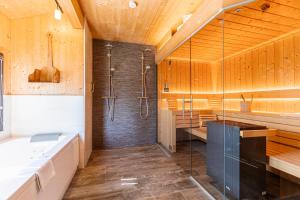 a bathroom with a shower and a tub and a sink at Alpenchalets Reiteralm by ALPS RESORTS in Schladming