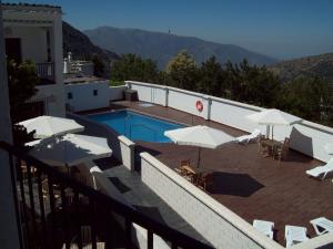 a swimming pool with white umbrellas and tables and chairs at Villa Turistica de Bubion in Bubión