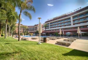 un complexe avec une piscine, des tables de pique-nique et un bâtiment dans l'établissement Ohtels Vil·la Romana, à Salou