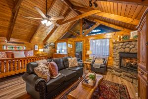 een woonkamer met een bank en een open haard bij Log Cabin, Hot Tub, Fireplace, Pool Table & Views! in Sevierville