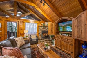 een woonkamer met een bank en een open haard bij Log Cabin, Hot Tub, Fireplace, Pool Table & Views! in Sevierville