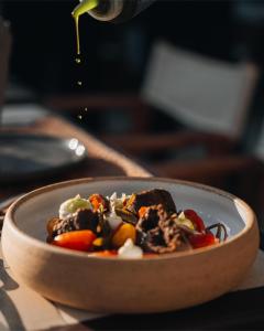 a bowl of food on a table with a person pouring sauce at Bratsera Boutique Hotel in Hydra