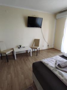 Habitación con cama y TV en la pared. en Ema Apartmani, en Vinkovci