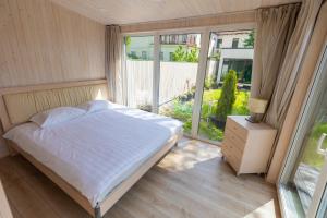 ein Schlafzimmer mit einem Bett und einem großen Fenster in der Unterkunft Baltic Beach Houses & Jomas in Jūrmala