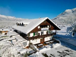 una casa cubierta de nieve con montañas en el fondo en Hotel Restaurant Hausberg Garmisch-Partenkirchen, en Garmisch-Partenkirchen