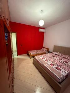 1 dormitorio con 2 camas y pared roja en Evelina Ernild Rooms, en Sarandë