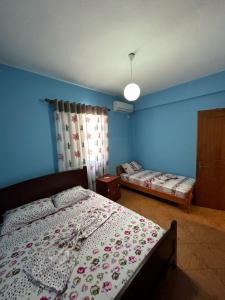 1 dormitorio con 2 camas y pared azul en Evelina Ernild Rooms, en Sarandë