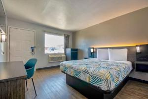 a hotel room with a bed and a desk and a window at Motel 6-Albuquerque, NM - Carlisle in Albuquerque