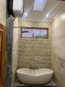 a bath tub in a bathroom with a window at Wikans Villa in Kuta