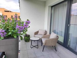 a balcony with two chairs and a table and flowers at Tabáň Marble apartment (city center & free parking) in Nitra