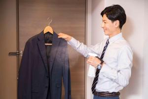 Un uomo tiene un vestito su un appendiabiti di Comfort Hotel Yamagata a Yamagata