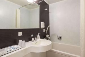 a bathroom with a white sink and a mirror at Comfort Hotel Kitakami in Kitakami