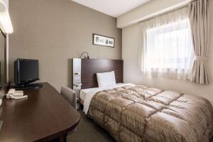 a hotel room with a bed and a desk with a computer at Comfort Hotel Kitakami in Kitakami