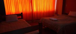 a bedroom with two beds and an orange curtain at ANDENES DEL TITICACA in Puno