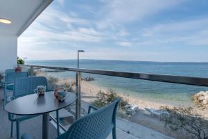 balcone con tavolo, sedie e vista sull'oceano di Beachfront Apartments Zanic a Podstrana