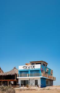 a building with a tiki sign on top of it at Tayta Surf House in Lobitos