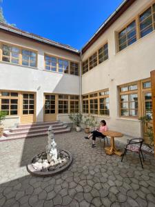 une femme assise sur un banc devant un bâtiment dans l'établissement Villa Alba by Akasha Retreat, à Bran