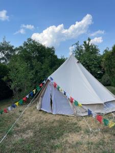 een witte tent in een veld met vlaggen bij Salève Glamping in Archamps