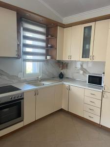 een keuken met witte kasten, een wastafel en een raam bij Sunny Luxury House Iraklitsa in Iraklitsa