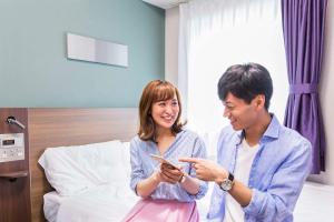 a man and a woman looking at a cell phone at Comfort Hotel Kokura in Kitakyushu