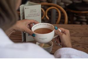 una mujer sosteniendo una taza de café sobre una mesa en Terrantai Lodge, en San Pedro de Atacama