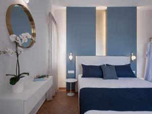 a bedroom with a bed with blue walls and a mirror at Elena Seafront Luxury Apartments in Almirida