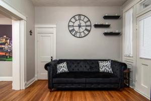 um sofá preto numa sala de estar com um relógio na parede em Charming New Orleans-Style Apartment with Gated Courtyard! em Little Rock