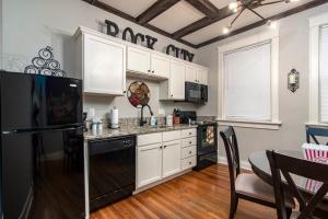 uma cozinha com armários brancos e um frigorífico preto em Charming New Orleans-Style Apartment with Gated Courtyard! em Little Rock