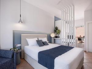 a bedroom with a large white bed and a chair at Elena Seafront Luxury Apartments in Almirida